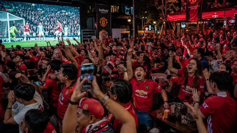 Manchester United fans watch a match on a big screen in Southeast Asia, with Betway branding visible in the background.